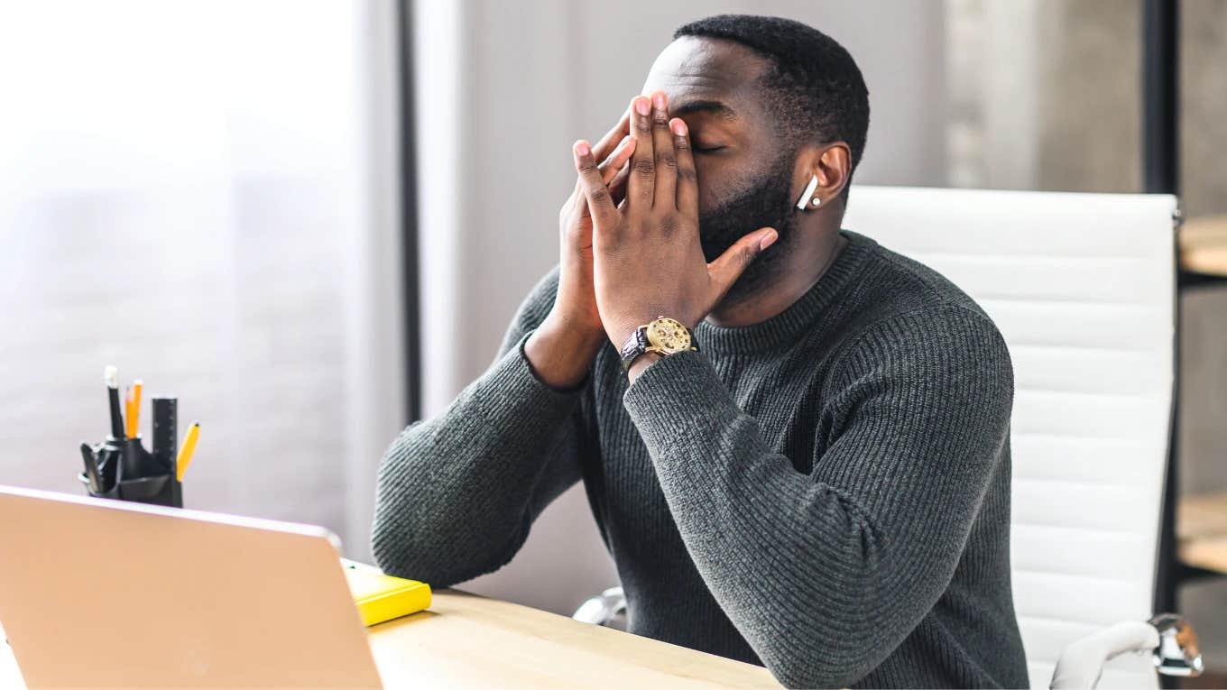 Man sitting with his head in his hands in front of computer