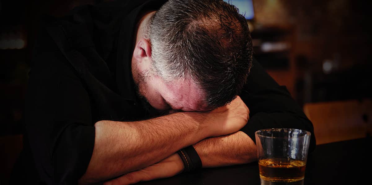 He Got Sober. I Got Broken. alcoholic man sitting at bar with his head down