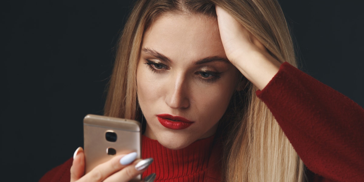 6 Ways To Avoid Being Catfished (And How To Catch One Red-Handed) woman looking at her phone