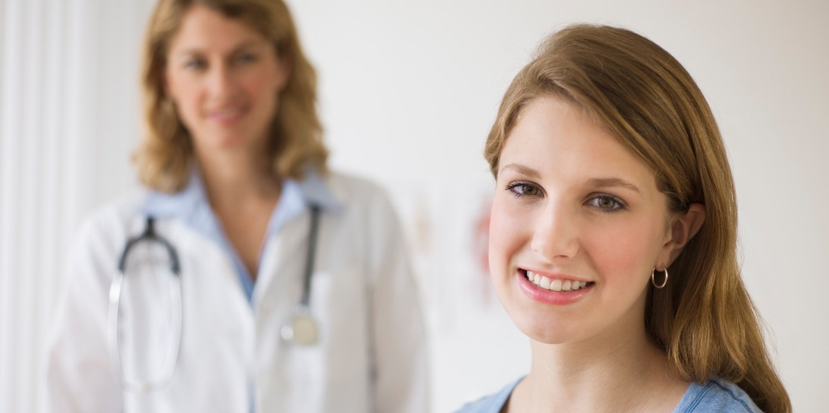 smiling woman with doctor in the background