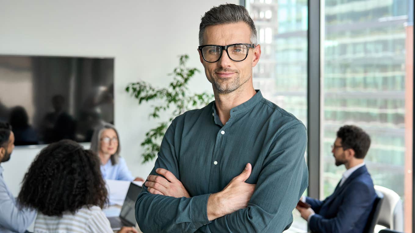 businessman leader looking at camera standing in office at team meeting