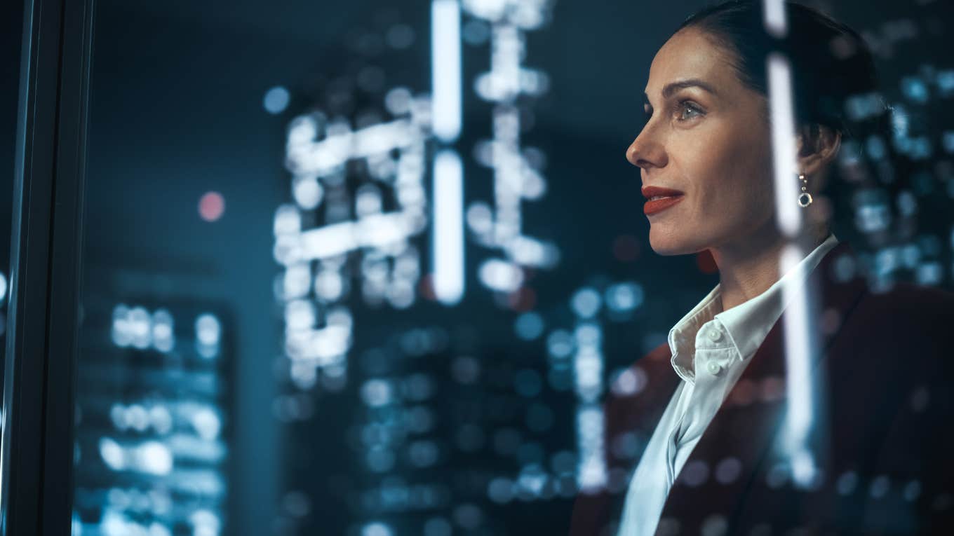 Businesswoman in Stylish Suit Working on Top Floor Office Overlooking Night City