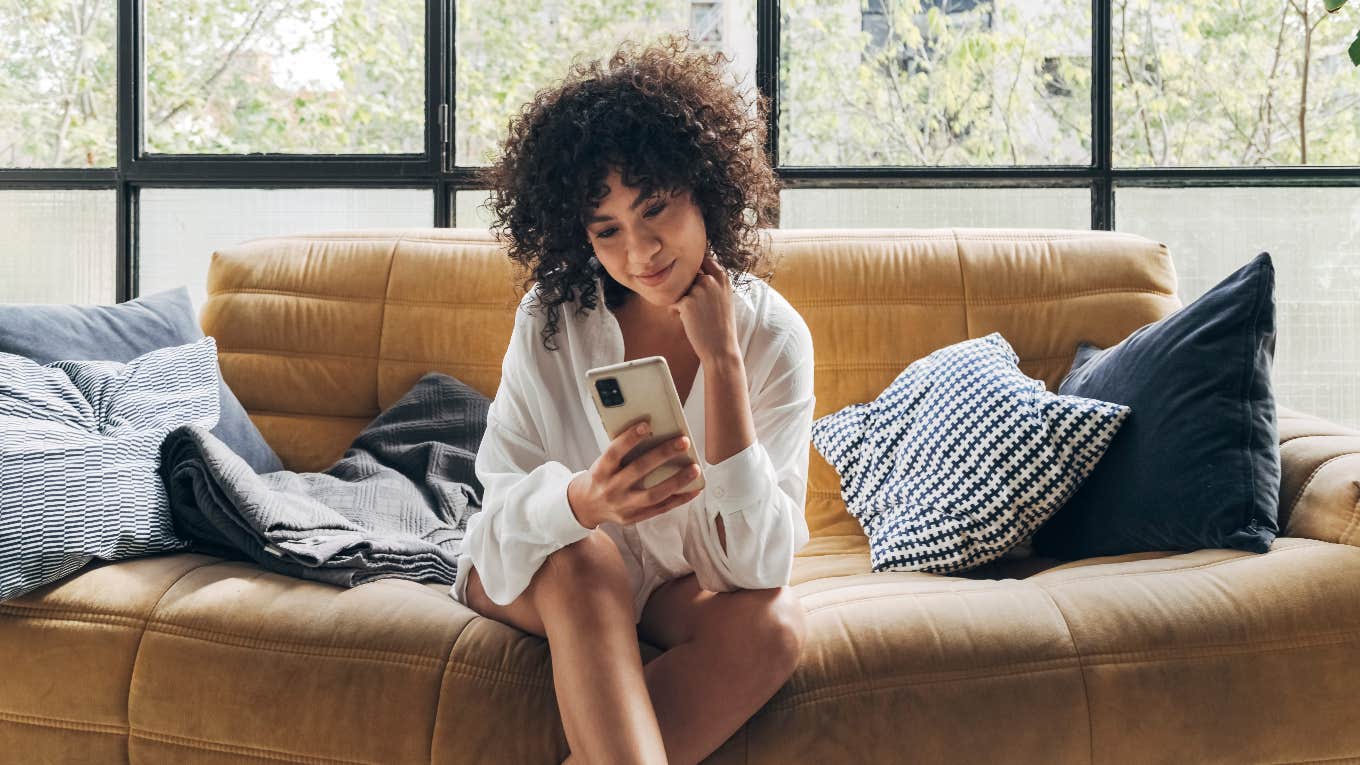 In Order To Change Your Life — Change Your Phone’s Wallpaper To One Specific Picture Woman looking at her phone on the couch