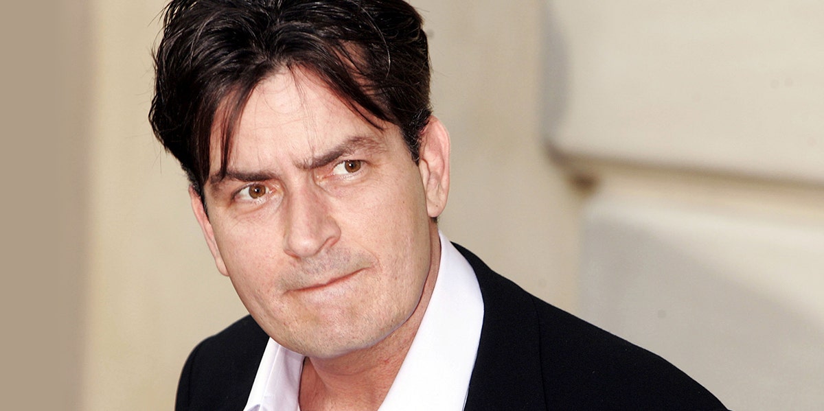 photo of Charlie Sheen in a suit and loose collar looking sideways at camera