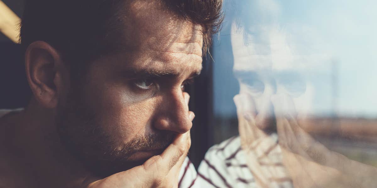 A distraught man looking out a window