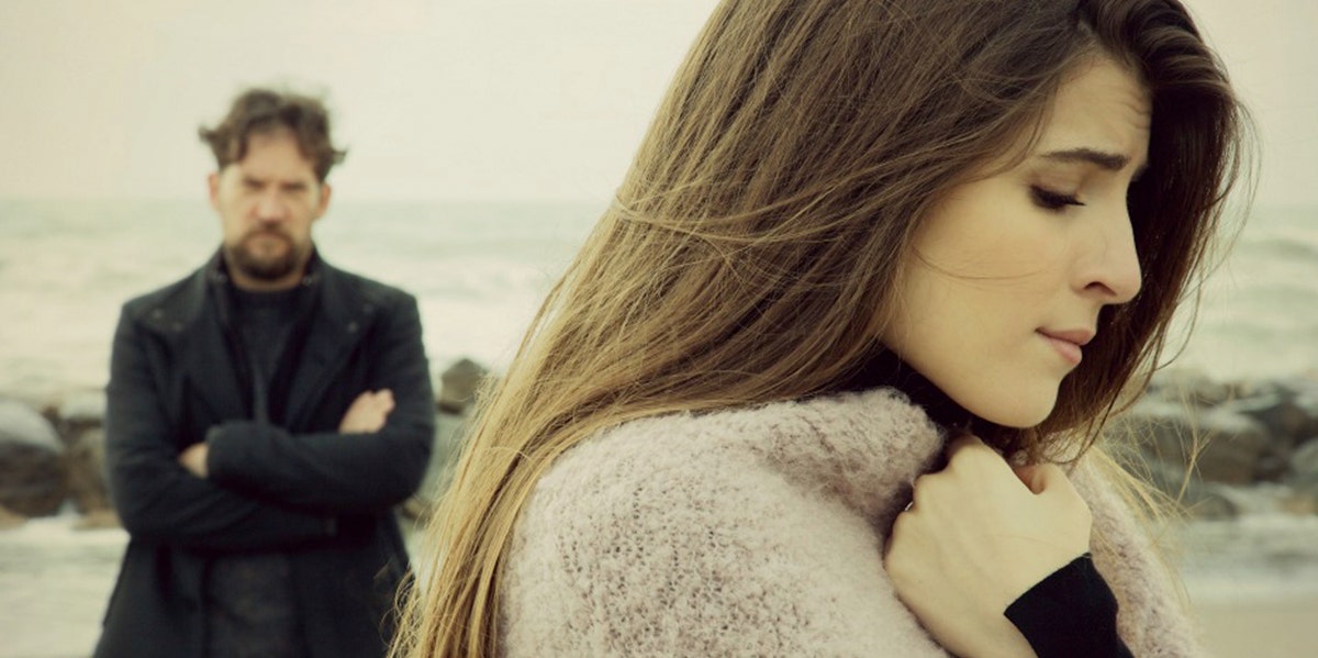 distraught women with man in black behind her