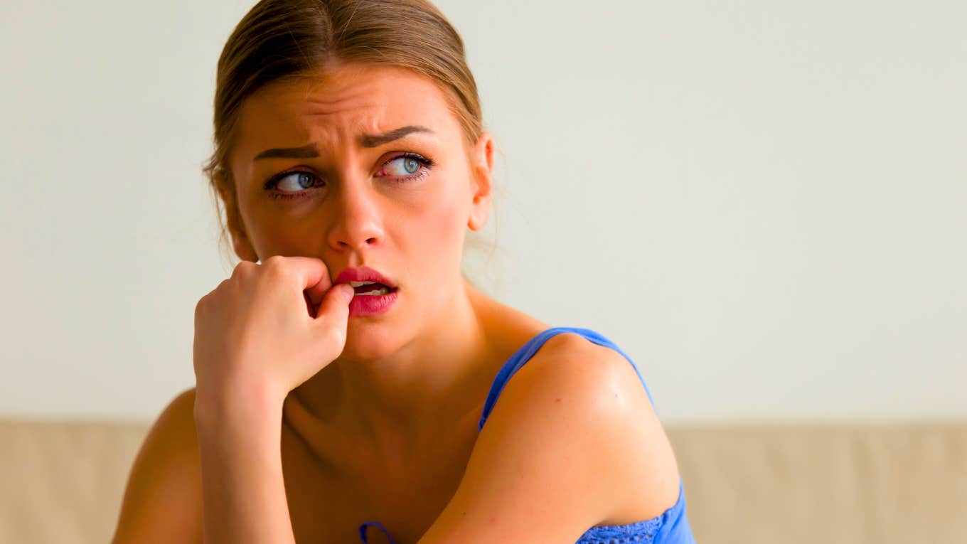 portrait of worried young woman biting nails