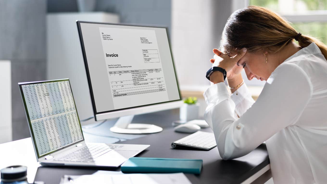 frustrated employee sitting in front of computers looking down at desk