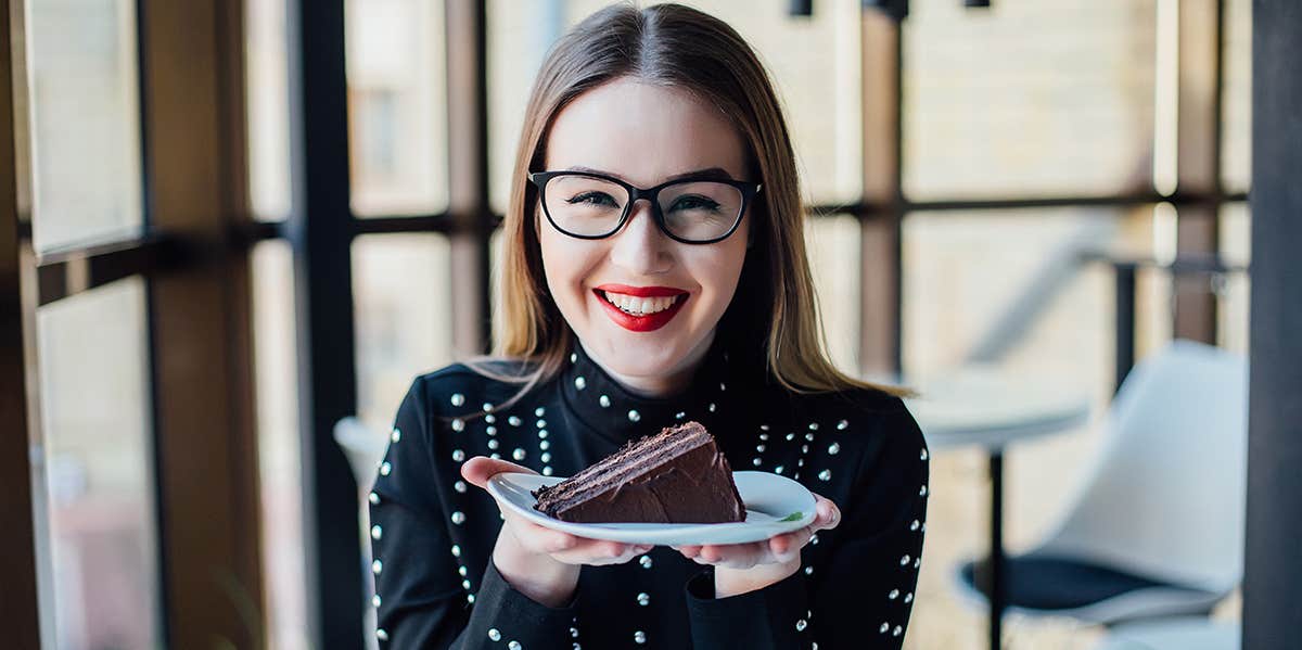 woman in glasses eating chocolate cake