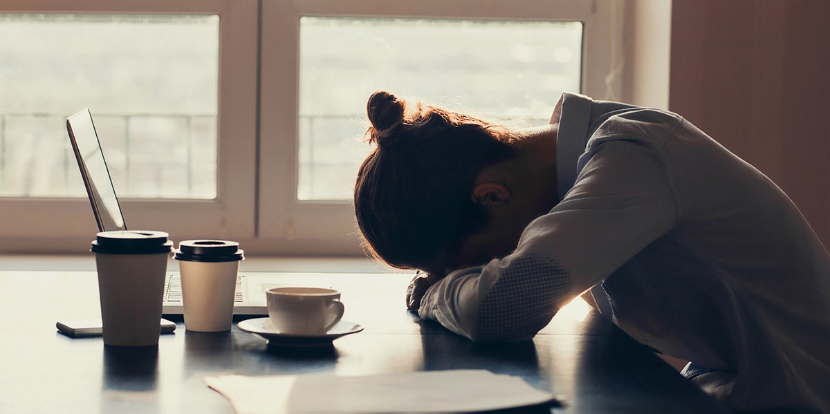 woman looking depleted with head against kitchen counter 