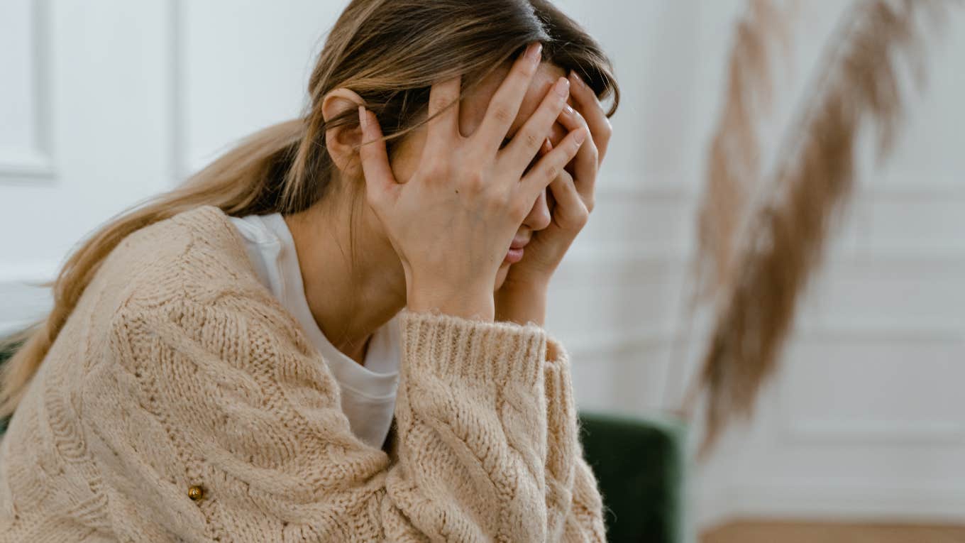 woman sitting with her hands covering her face