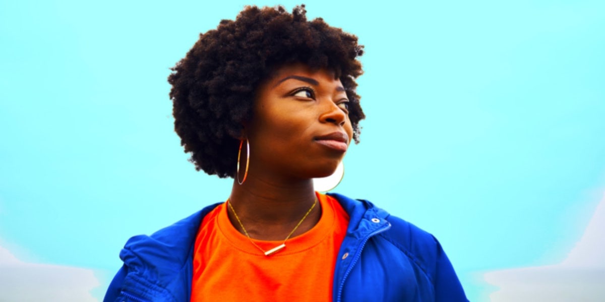 woman in blue jacket staring off blue background