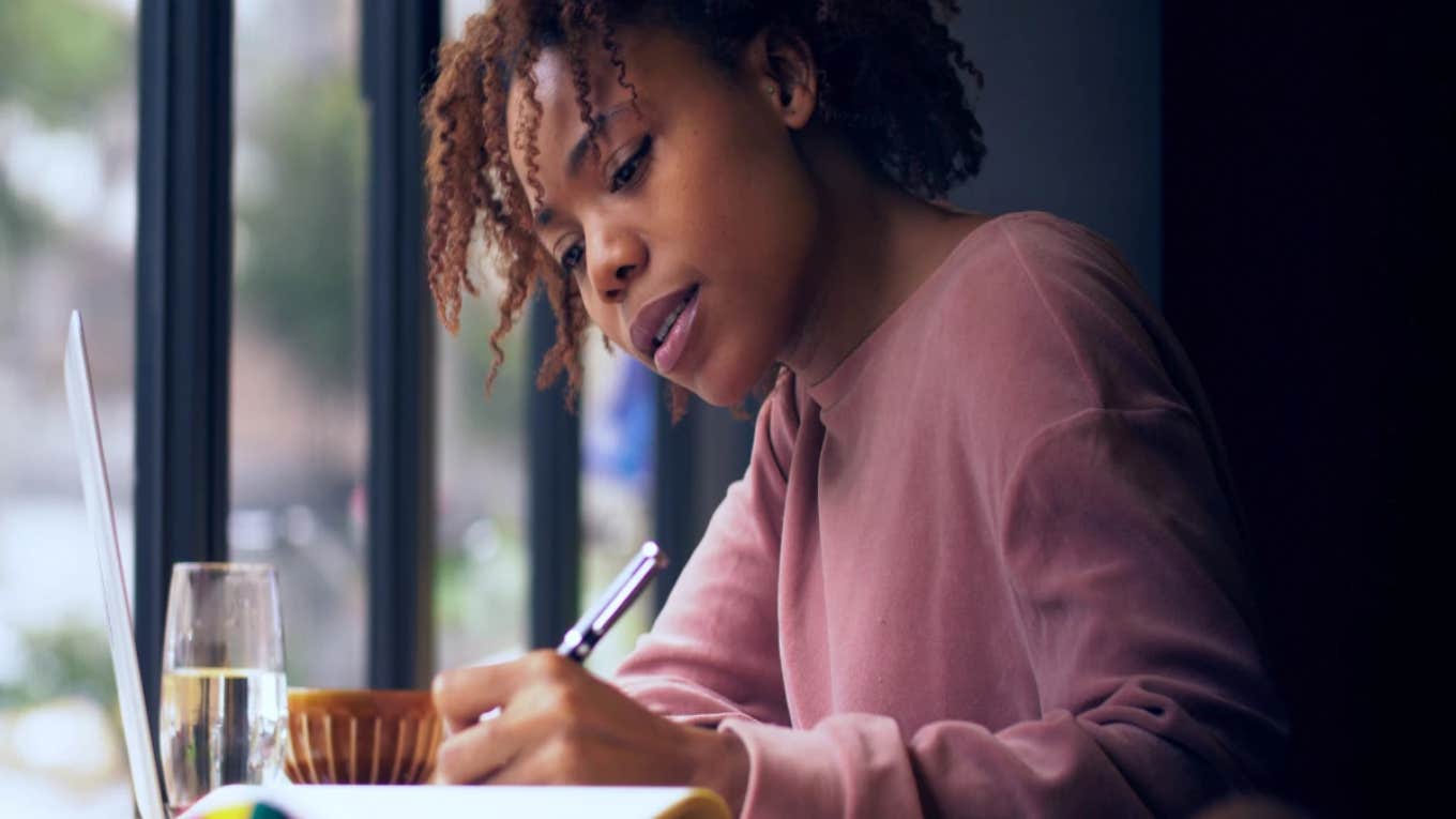 college student writing by the window