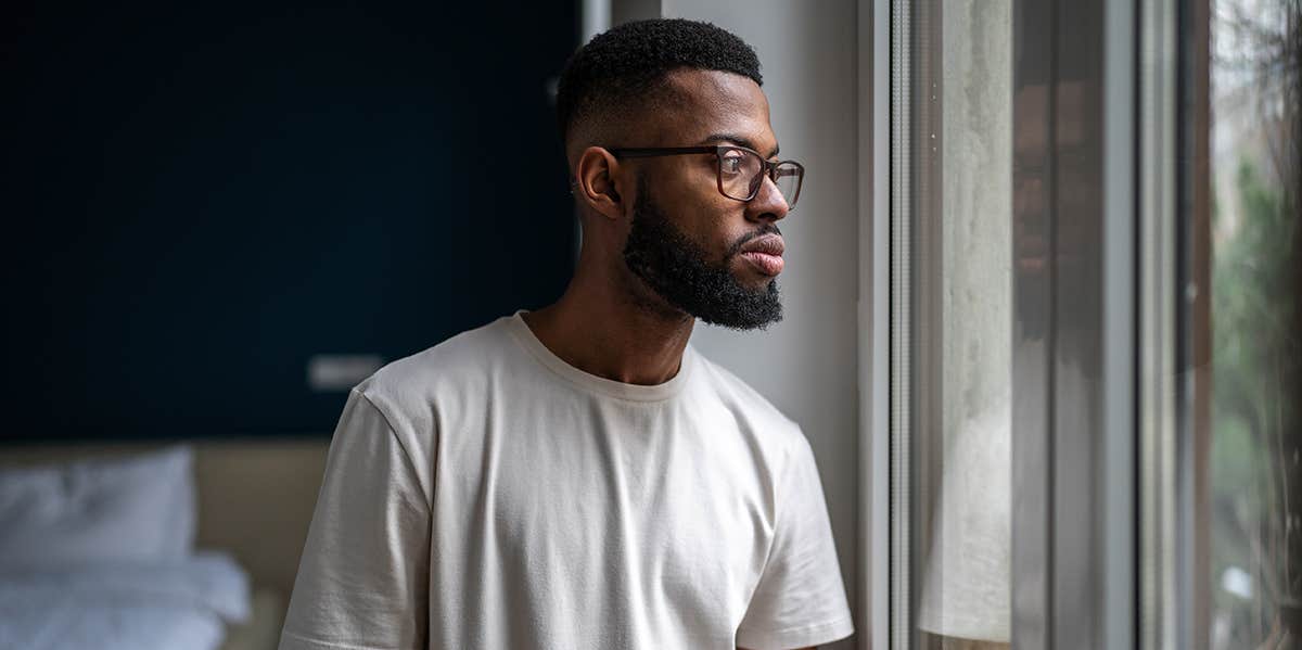 man looking out window in thought