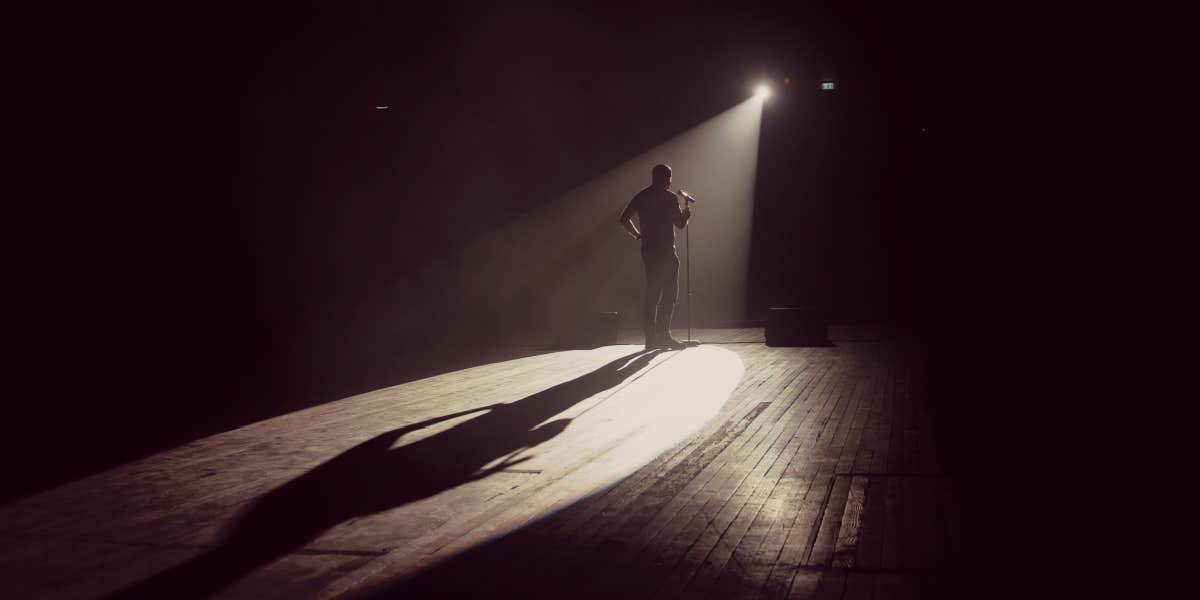 communication lessons from stand up comedy man on a stage doing comedy, backlit by spotlight