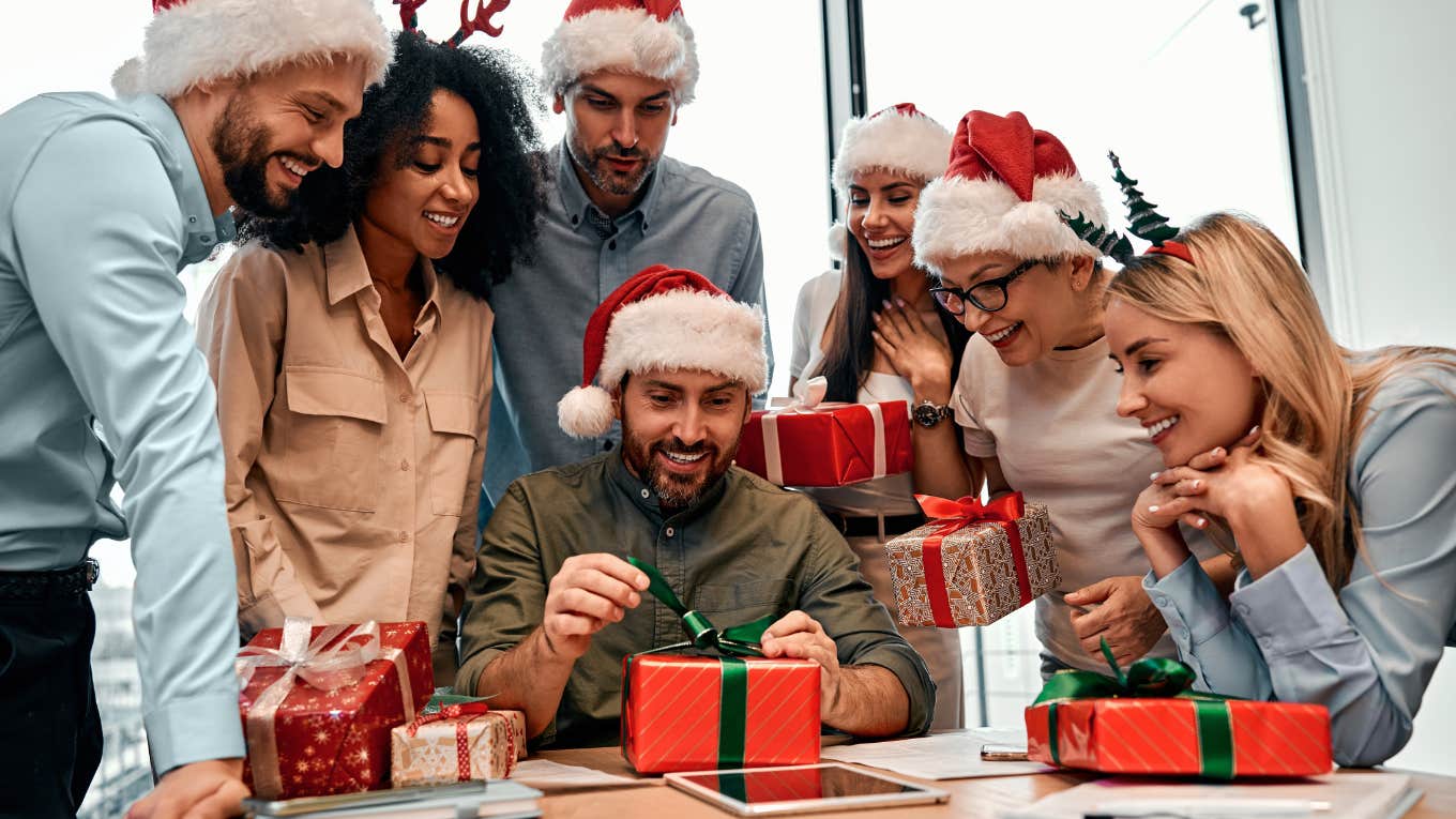 Group of business people in Santa hats, colleagues unpacking gifts at work in the office.