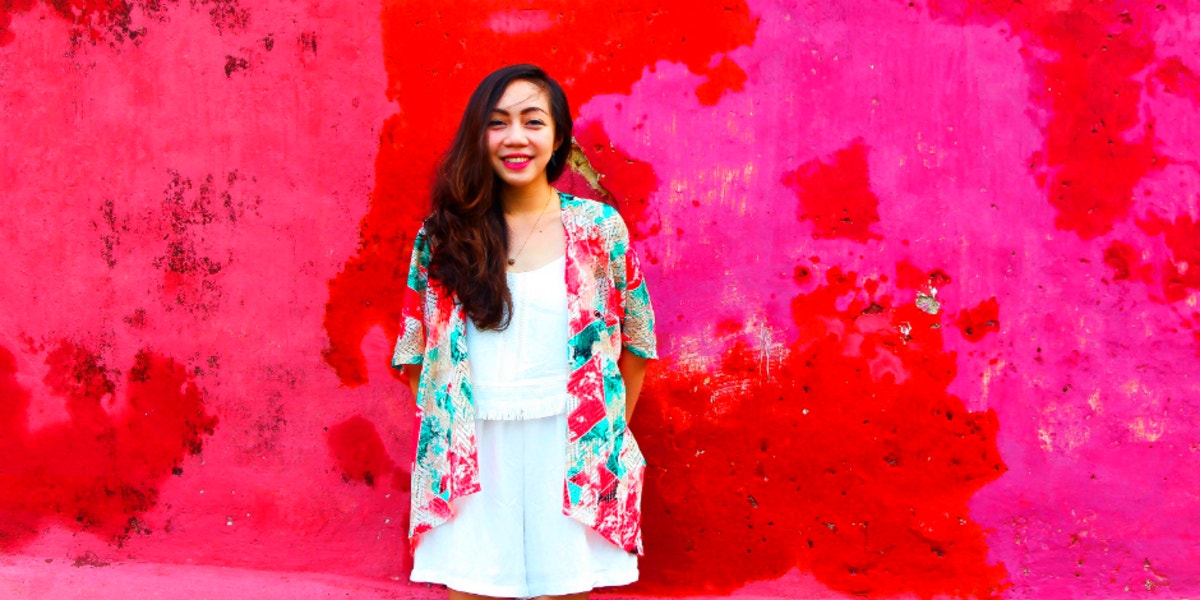 confident woman standing against pink background