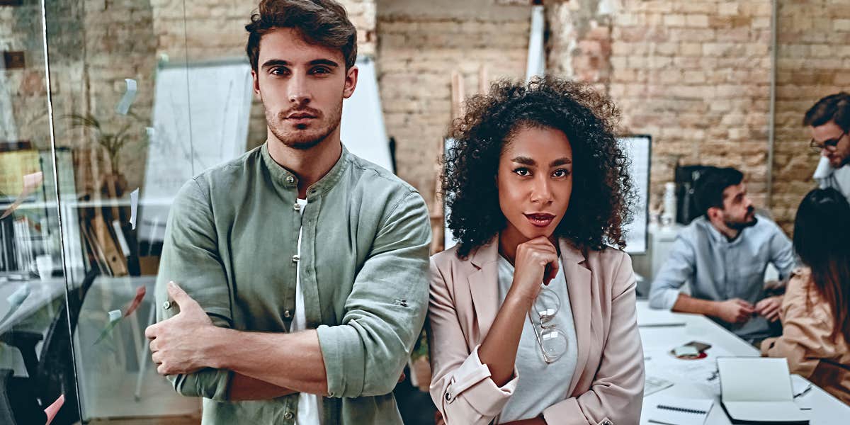 Two employees in their thirties in the workplace, looking like they are in conflict