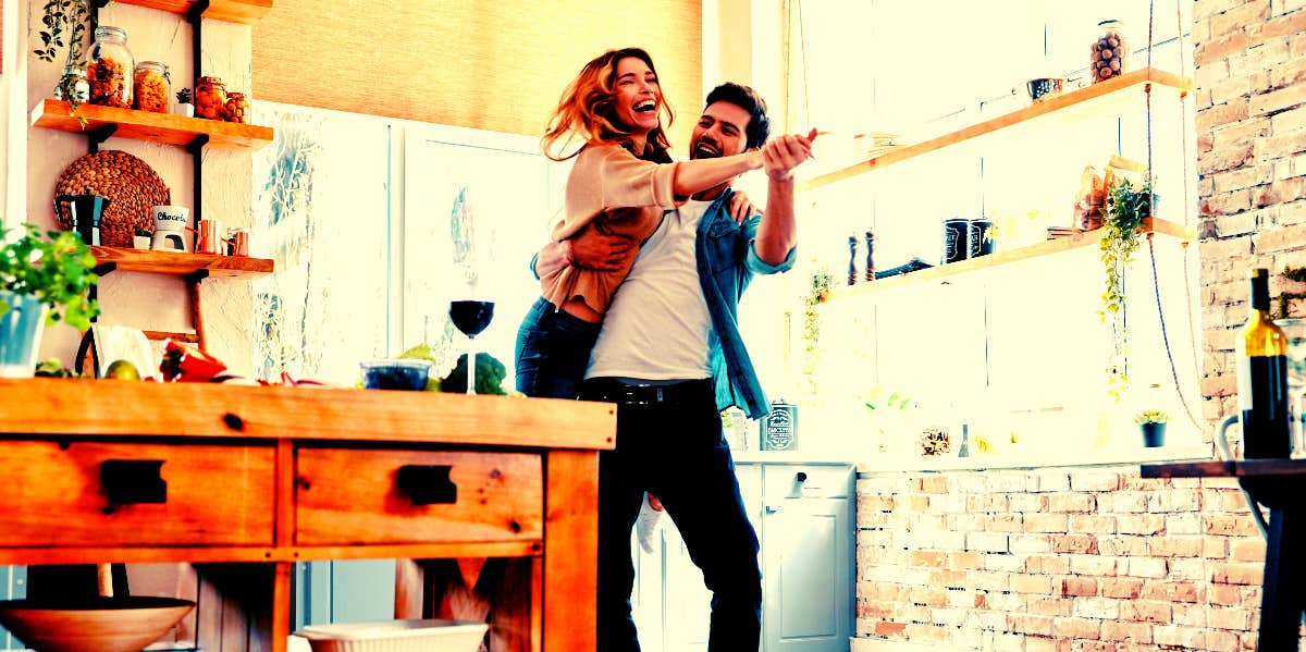 man and woman cooking and dancing in the kitchen