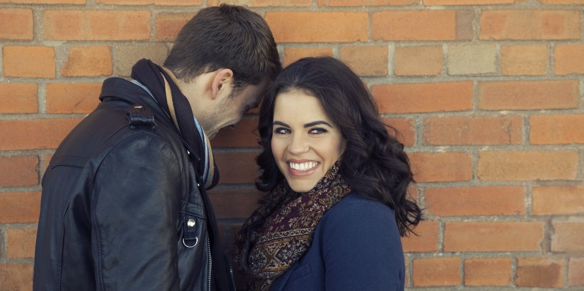 man and woman standing by a brick wall