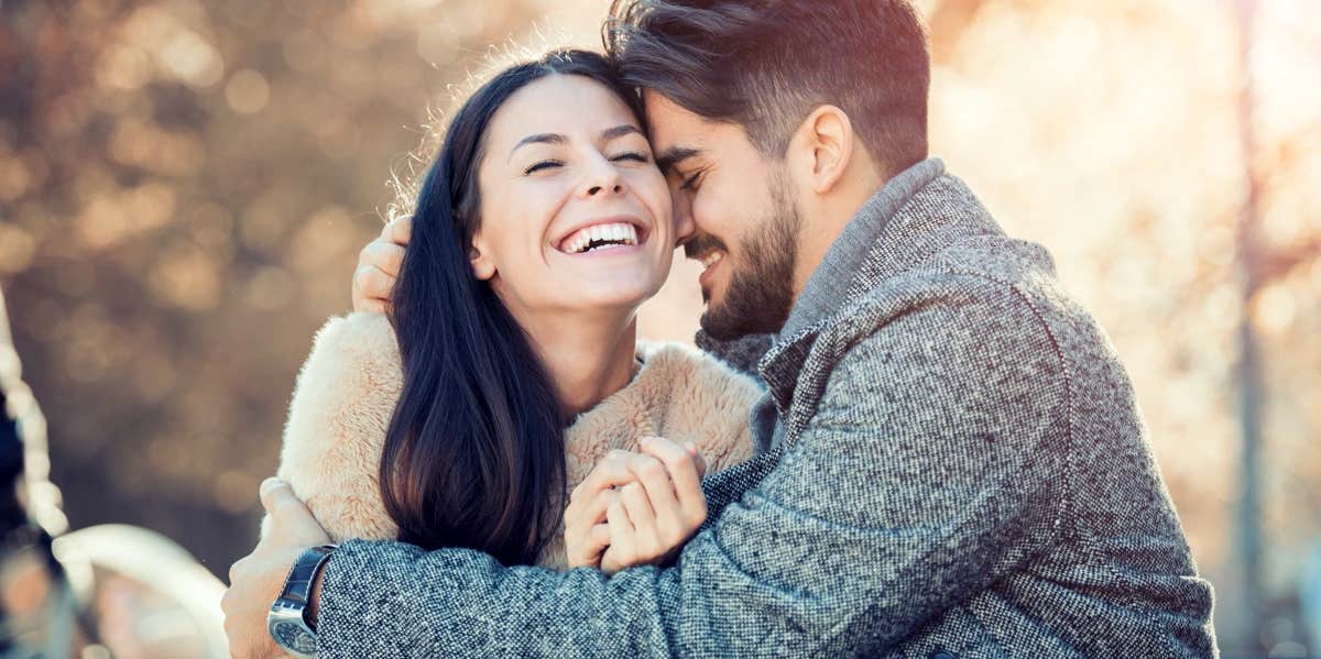 A couple share a close bonding moment. He places his head to hers, she smiles with love