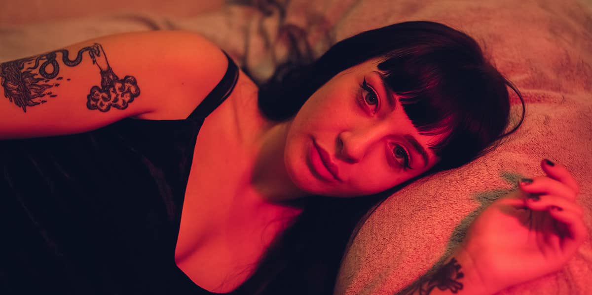 Could relationship insecurity be killing your sex drive? girl laying in bed with red light shining