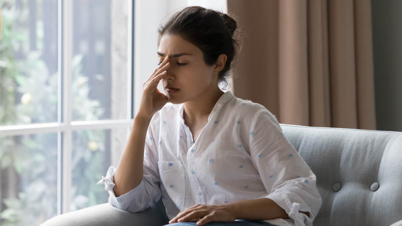 woman sitting on couch holding her head