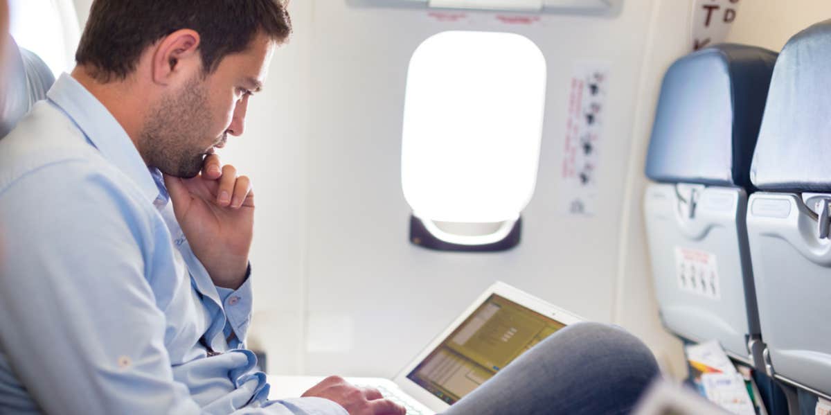 Couple Angry That Fellow Plane Passenger Turned On Reading Light To Work At 8AM Man working on an airplane