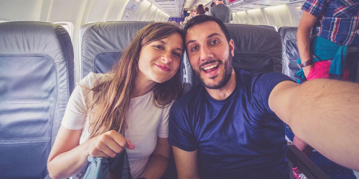 couple taking a selfie while sitting on an airplane