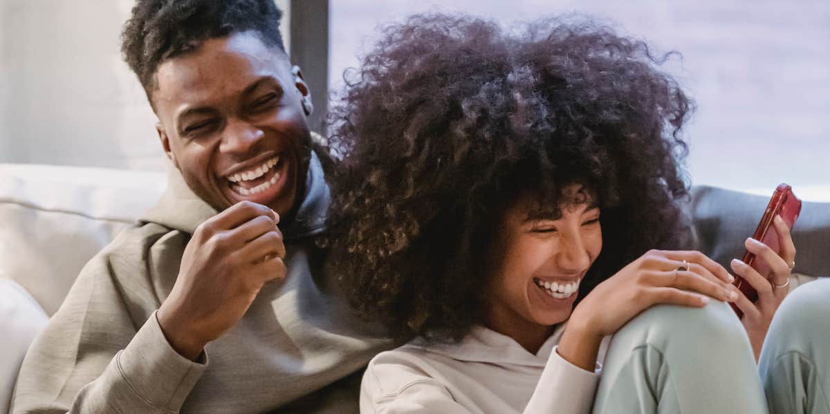 Woman's Boyfriend Expects Her To Financially Support Him Since She's The Breadwinner Couple laughing on couch