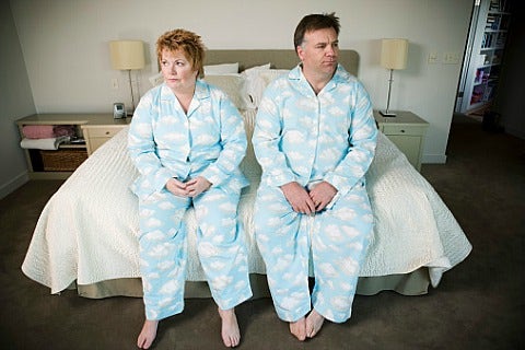 couple sitting on bed in matching pajamas couple sitting on bed in matching pajamas