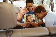 parents buckling a baby into a car seat