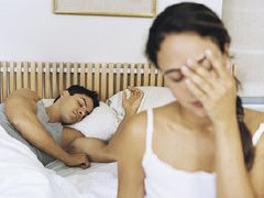 couple in bed man asleep woman with head in hand
