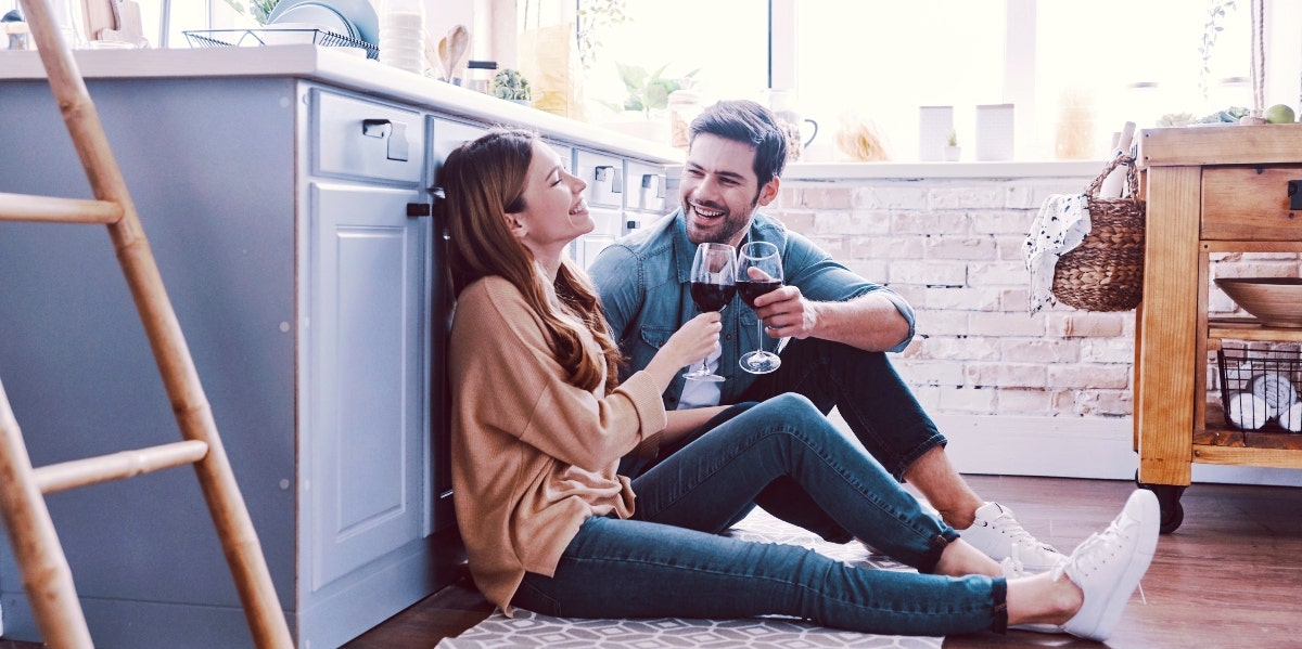 couples first house man and woman sitting on the floor of a kitchen drinking wine