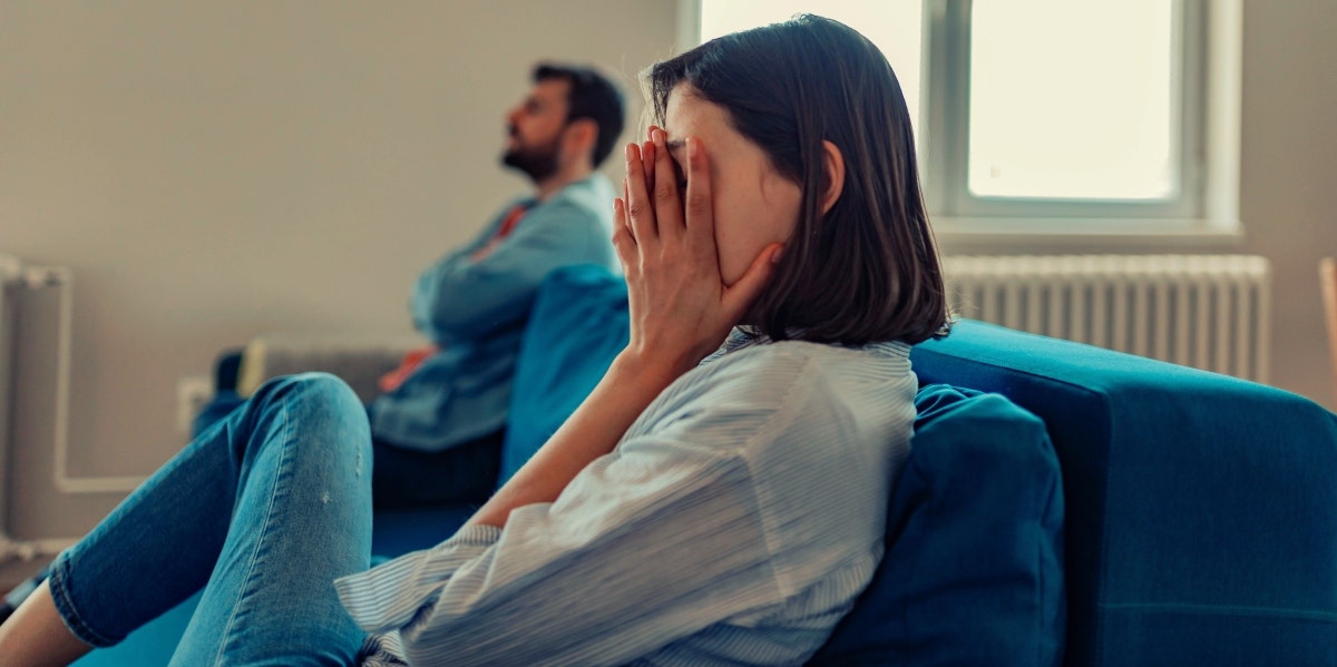 upset woman sitting on the couch with man