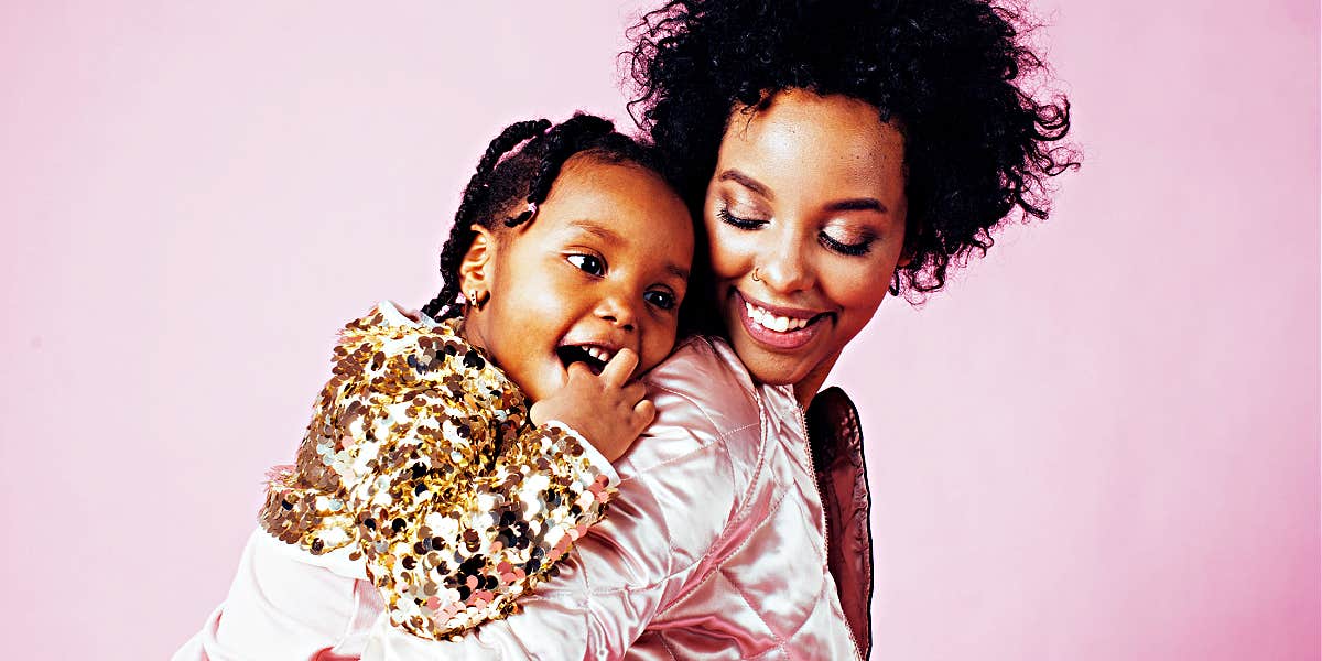 How to build the strongest bond with your kids pretty young mom smiling at preschool daughter on her back, with a pink background