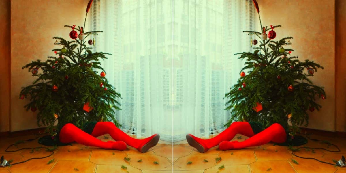 10 Creepy Christmas Songs That Are Actually Pretty Scary person sitting behind a Christmas tree