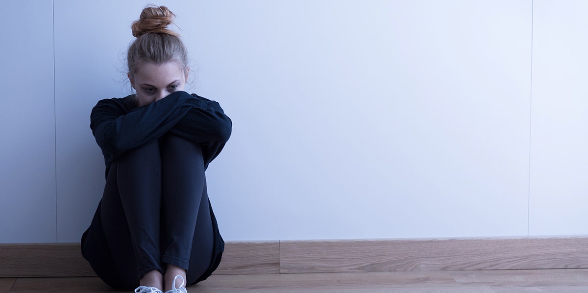 woman hugging chest against wall