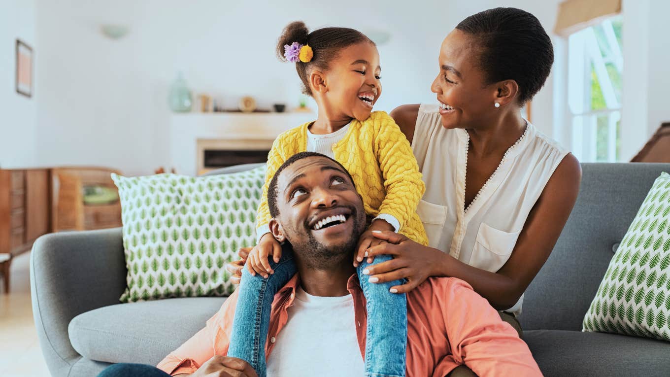 Criminology Graduate Shares The Number One Safety Hack She Recommends All Families Start Using little girl sitting on father shoulder while playing with mother at home