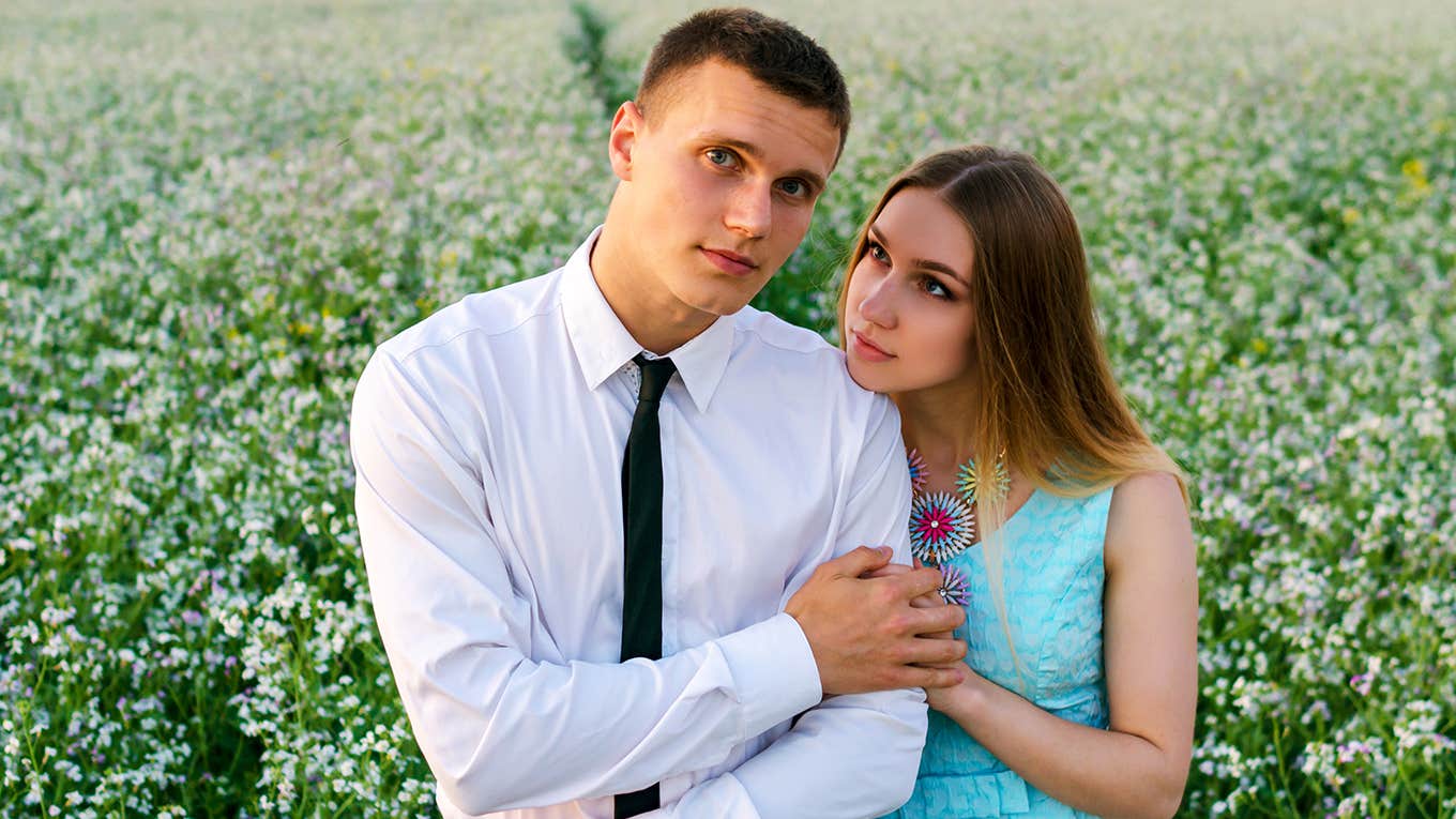 Romantic couple running in field holding hands.