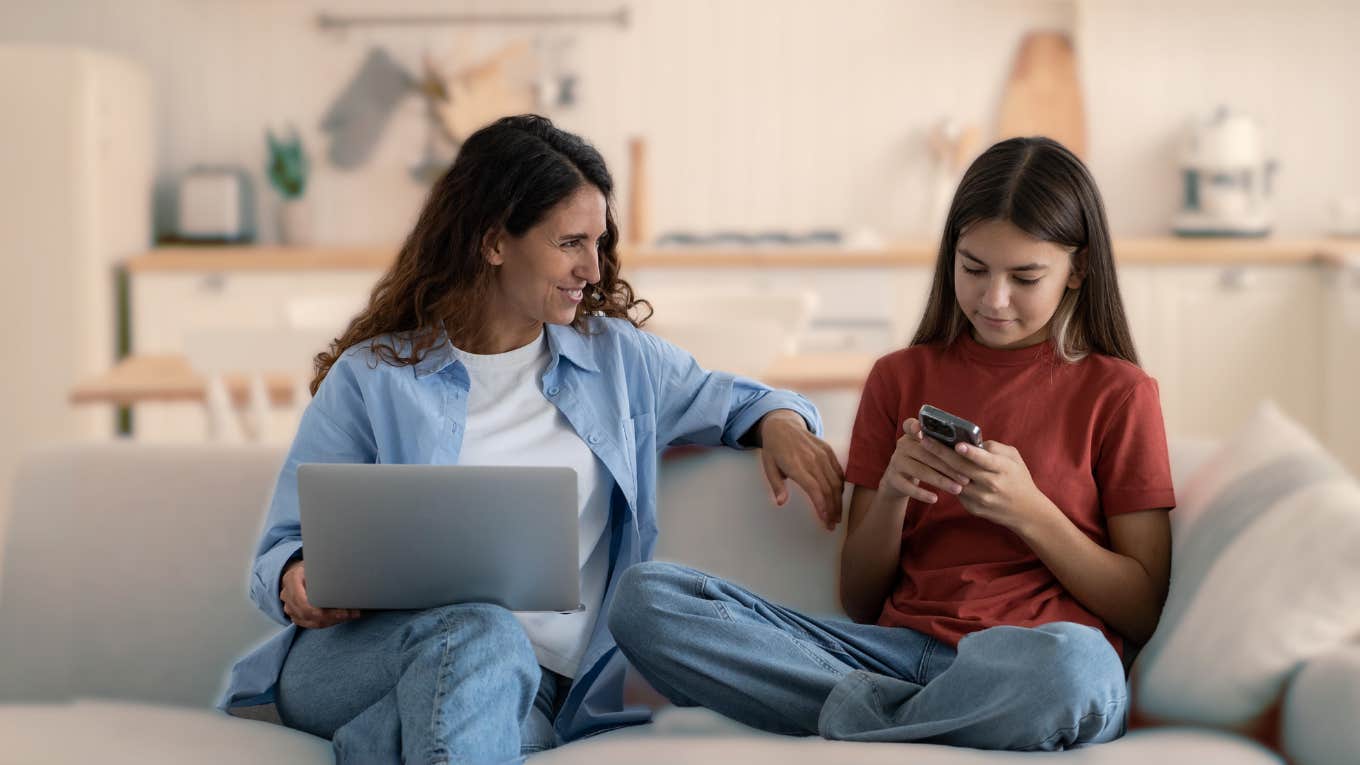 mom and teen daughter on the couch talking while teen looks at phone