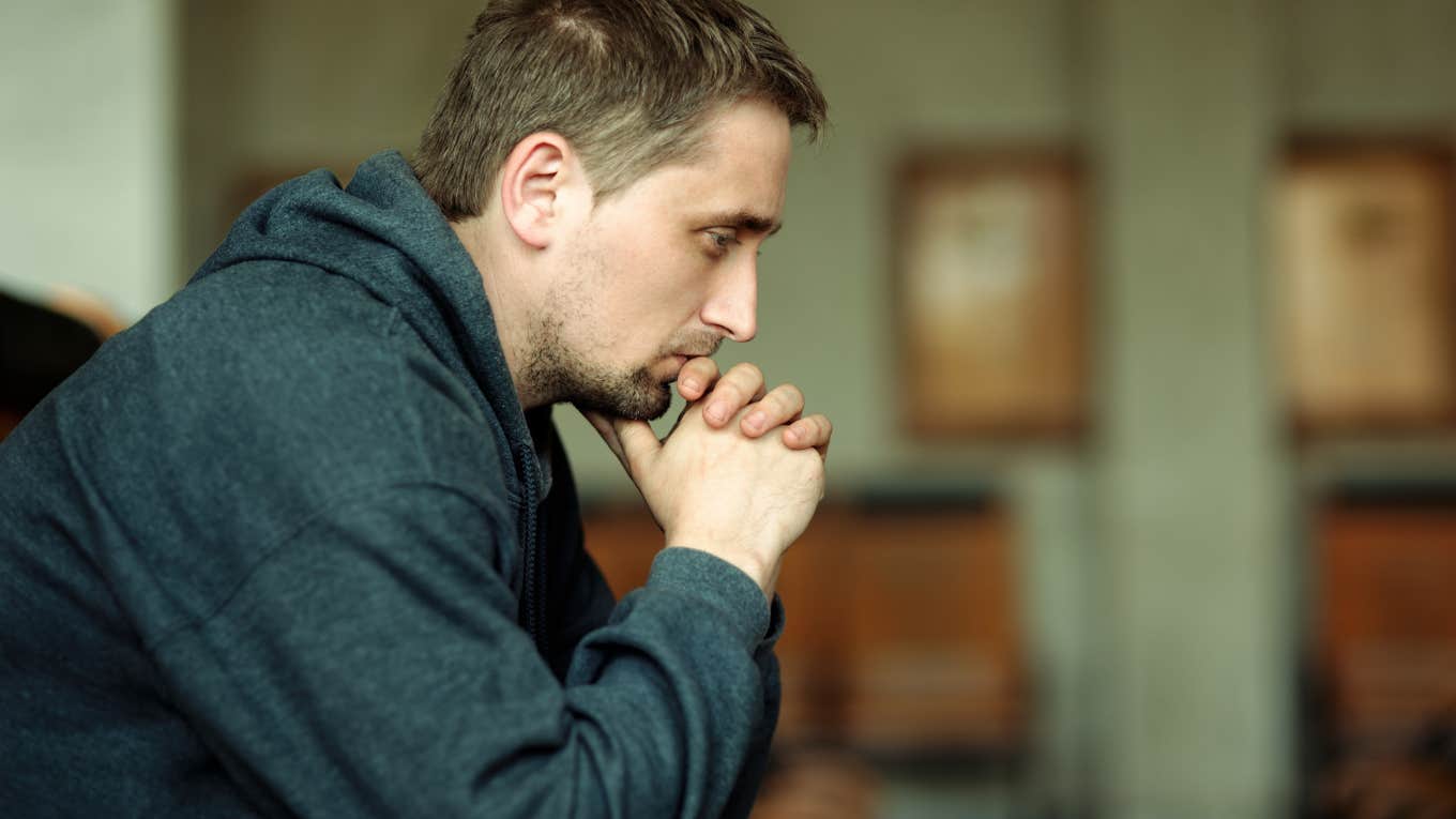 side shot of serious man sitting on couch with hands under chin