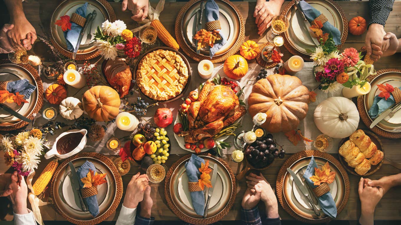 group of people holding hands around thanksgiving dinner table