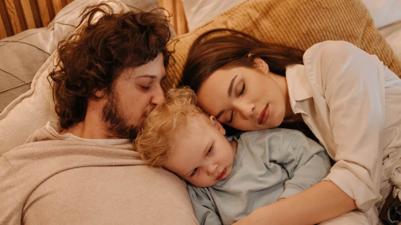 mother and father laying with toddler boy