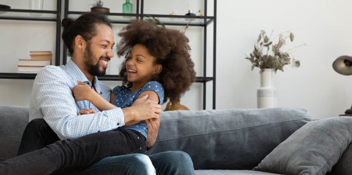 dad cuddling daughter on a couch