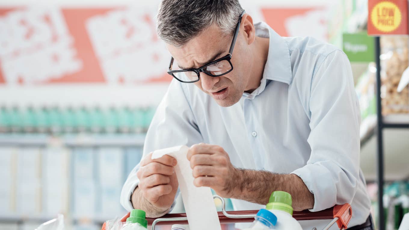 man looking at expensive grocery store receipt