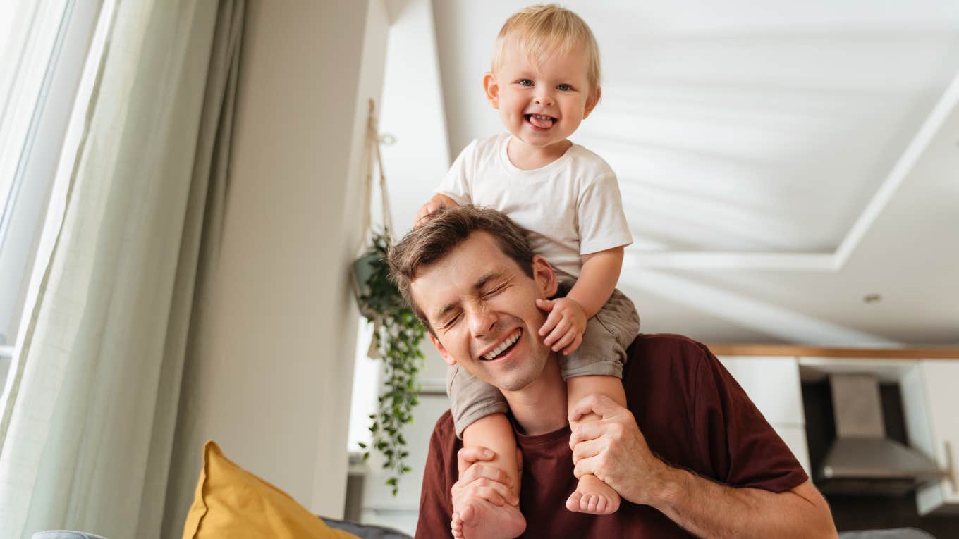 Laughing father giving his kid piggyback ride on shoulders