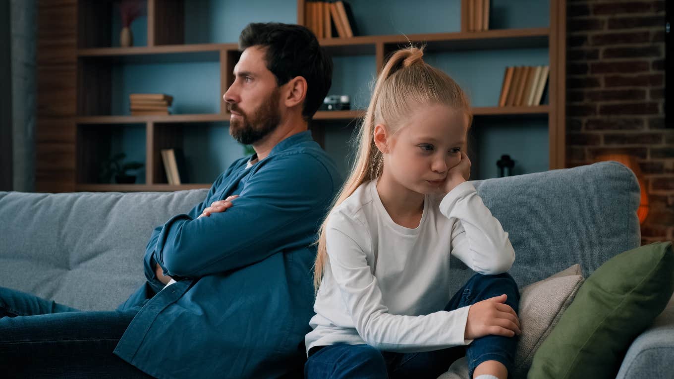 father and daughter sitting on couch facing opposite directions, upset