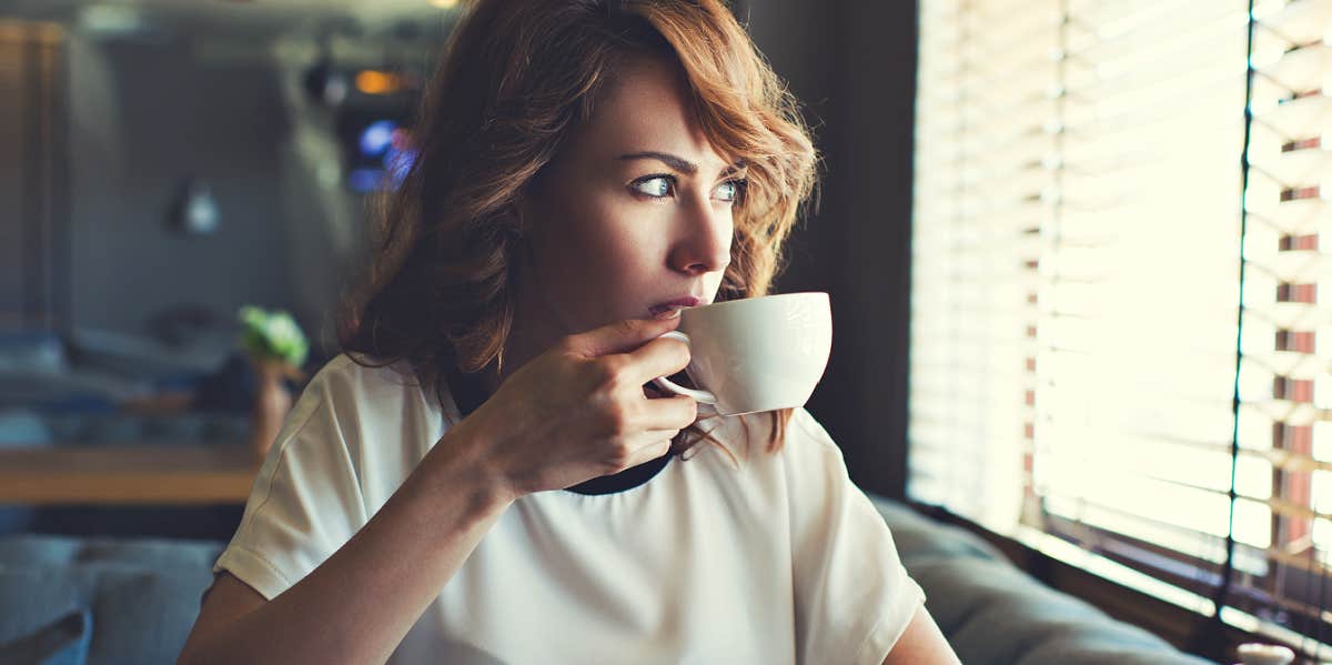 woman pensively sipping coffee in a fancy diner
