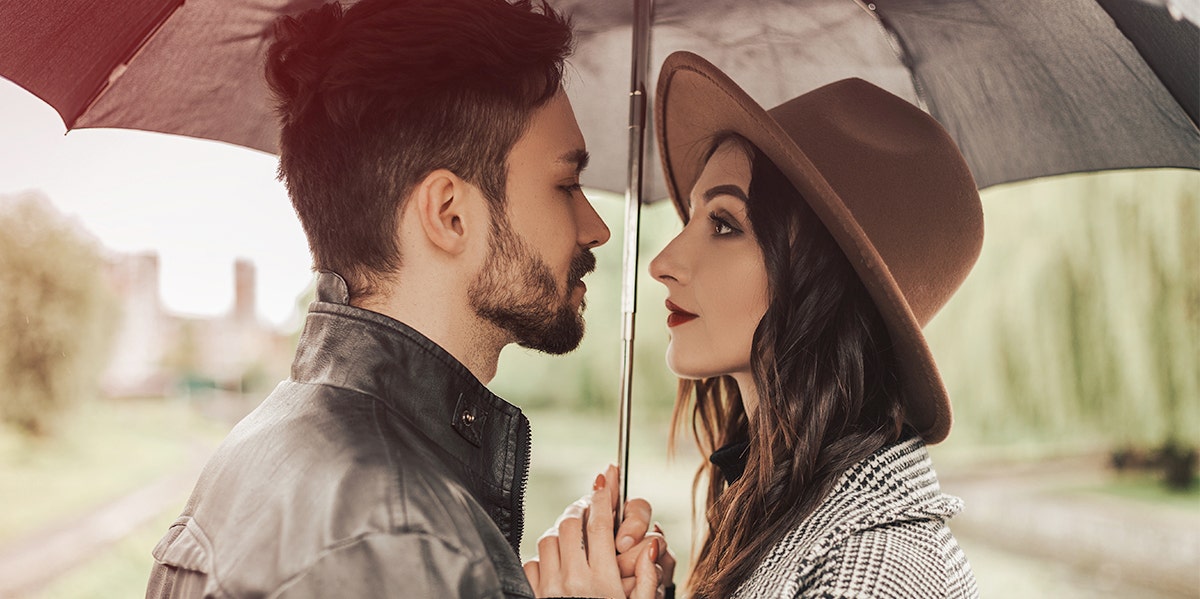 man and woman standing under umbrella looking at each other